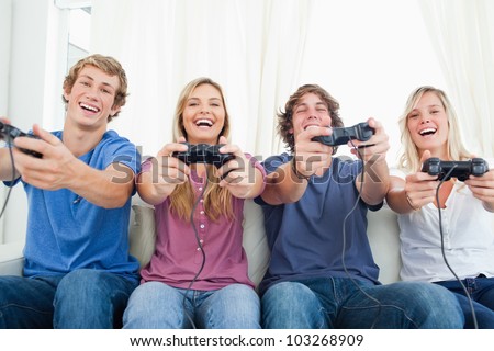 A group playing video games and smiling as they all look into the camera