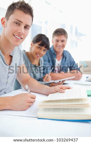A close up shot of  studying friends as they look into the camera and smile