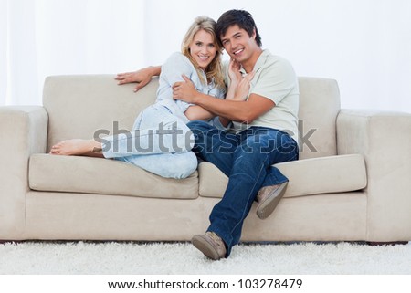 A young couple are sitting down on a couch embracing each other