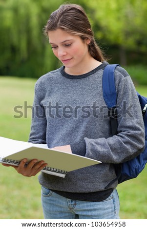 Young relaxed woman reading her notebook while standing in the countryside