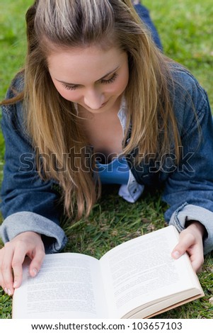 Young relaxed girl lying on the grass in the countryside while reading a book