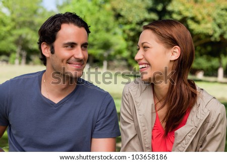 Man is grinning while he watches his friend who is gleefully laughing in a bright grassland area