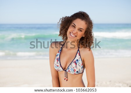 Smiling young woman leaning her head on the side while standing in front of the sea