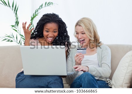 Two laughing women sitting down with a laptop and a bank card