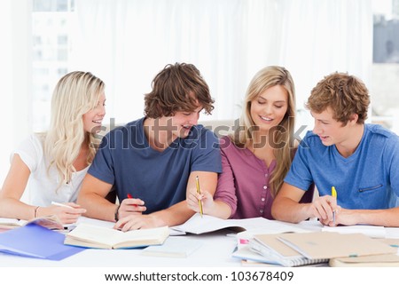 A group of students laughing together as they all study the work