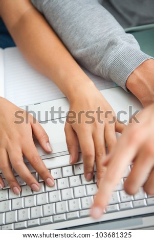 High view of students hands working with a laptop while typing and pointing the screen