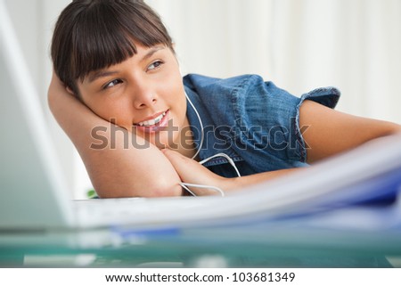 Female student with earphones looking away at homework time