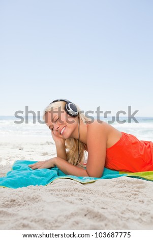 Young blonde woman lying down while listening to music with her headset