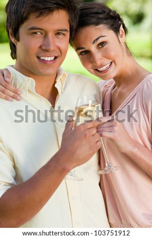 Woman smiling and leaning against her smiling friend while touching glasses of champagne in celebration