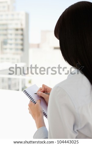 A woman with her back to the camera starts writing on her notepad