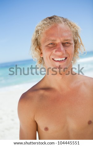 Smiling blonde man looking at the camera while standing in front of the ocean