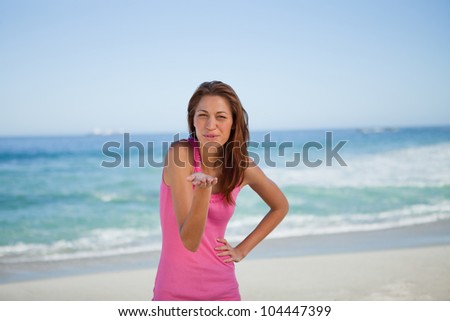 Young woman blowing an air kiss while standing in front of the sea