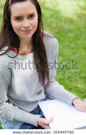 Young calm girl sitting in the countryside while holding her school books