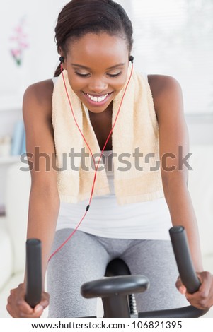 Black woman on a bike listening music while smiling in a living room