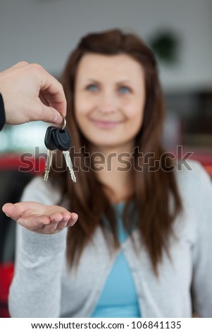 Happy brunette receiving car keys in a garage