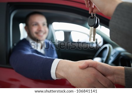 Woman giving car keys while shaking hand in a dealership