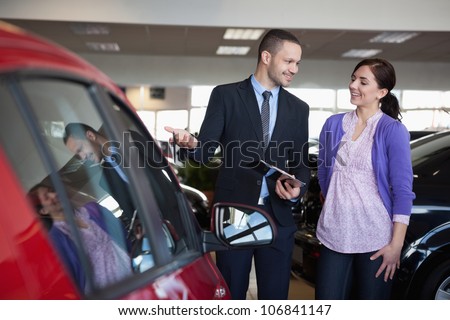 Salesman showing a car to a woman in a car shop