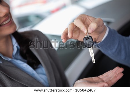 Smiling woman receiving keys from someone in a car shop