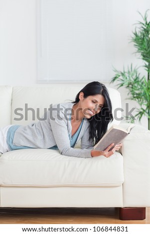 Smiling woman reading a book while she lays on a couch in a living room