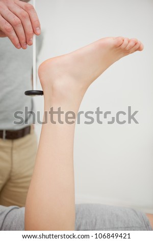Doctor checking the reflexes of the ankle of a patient in a medical room