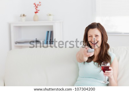 Smiling woman pressing a remote control in a living room