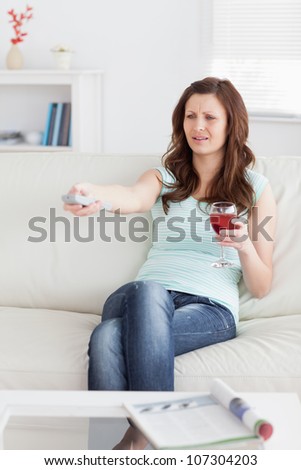 Woman pressing a remote control while sitting in a living room
