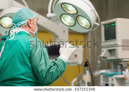 Surgeon wearing surgical equipment raising his arm in a surgical room