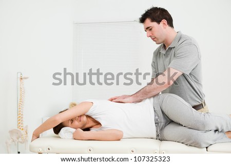 Brunette woman lying on the side while being massaged in a medical room