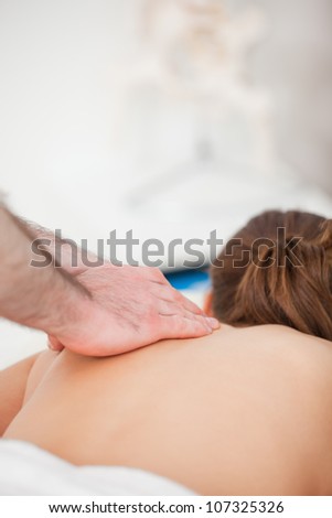 Chiropractor massaging the back of his patient indoors