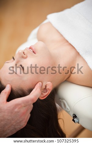 Woman lying on the back while being massaged on her head in a room