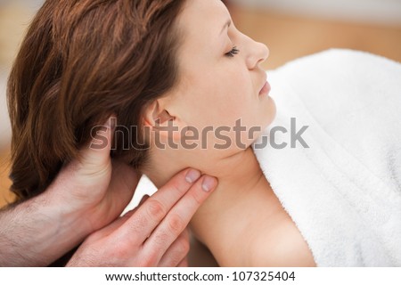 Therapist massaging the neck of woman while holding her head in a room
