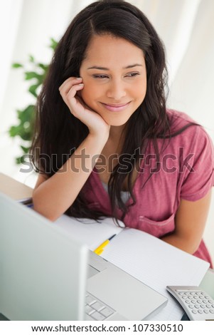 Smiling brunette student looking outside at her desk