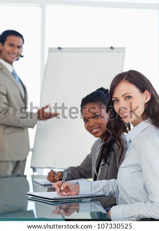 Young smiling employees working during a presentation and writing in a notebook
