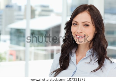 Young and smiling executive woman standing upright in front of the bright window