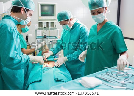 Nurse holding surgical tool next to operating table in an operating theatre