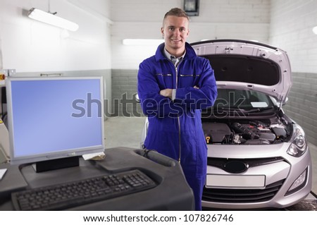 Mechanic next to a car and a computer in a garage