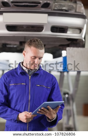 Mechanic looking at a tablet computer while holding it in a garage