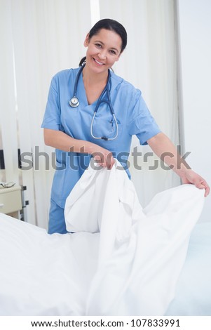 Nurse changing sheets on the bed in hospital ward