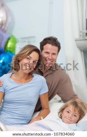Child on a medical bed next to his parents in hospital ward