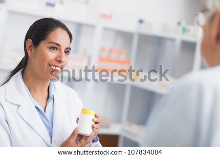 Pharmacist holding a drug box while looking at a patient in hospital