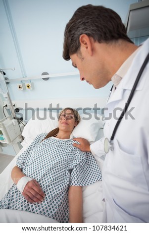Doctor touching the shoulder of his patient in hospital ward