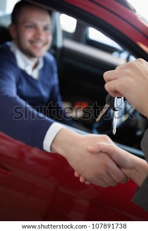 Customer receiving car keys while shaking hand in a garage