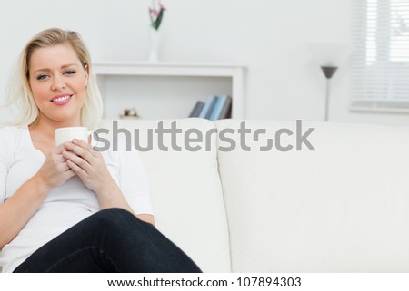 Woman on a sofa drinking a coffee in a lounge