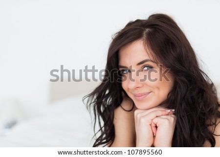 Smiling woman lying on her white duvet in her bedroom