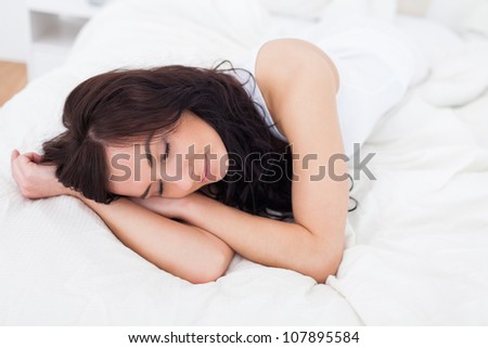 Woman falling asleep on her bed in her bright bedroom