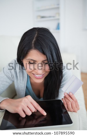 Woman touching a tactile tablet screen while holding a credit card in a living room