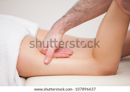 A masseur massaging the thigh of a woman while holding her ankle indoors