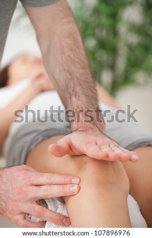 Physiotherapist using his hand palm to massage a knee indoors