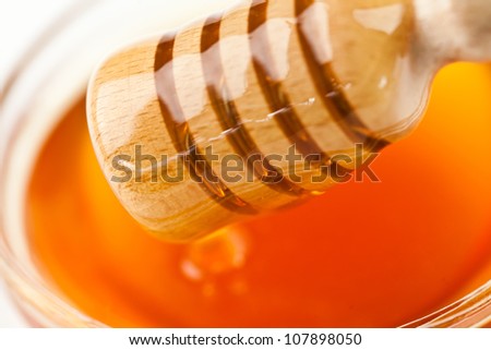 Honey dipper outgoing a honey bowl against a white background
