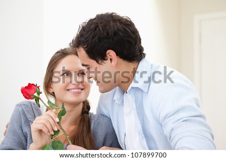 Man offering a rose to a Woman while embracing indoors